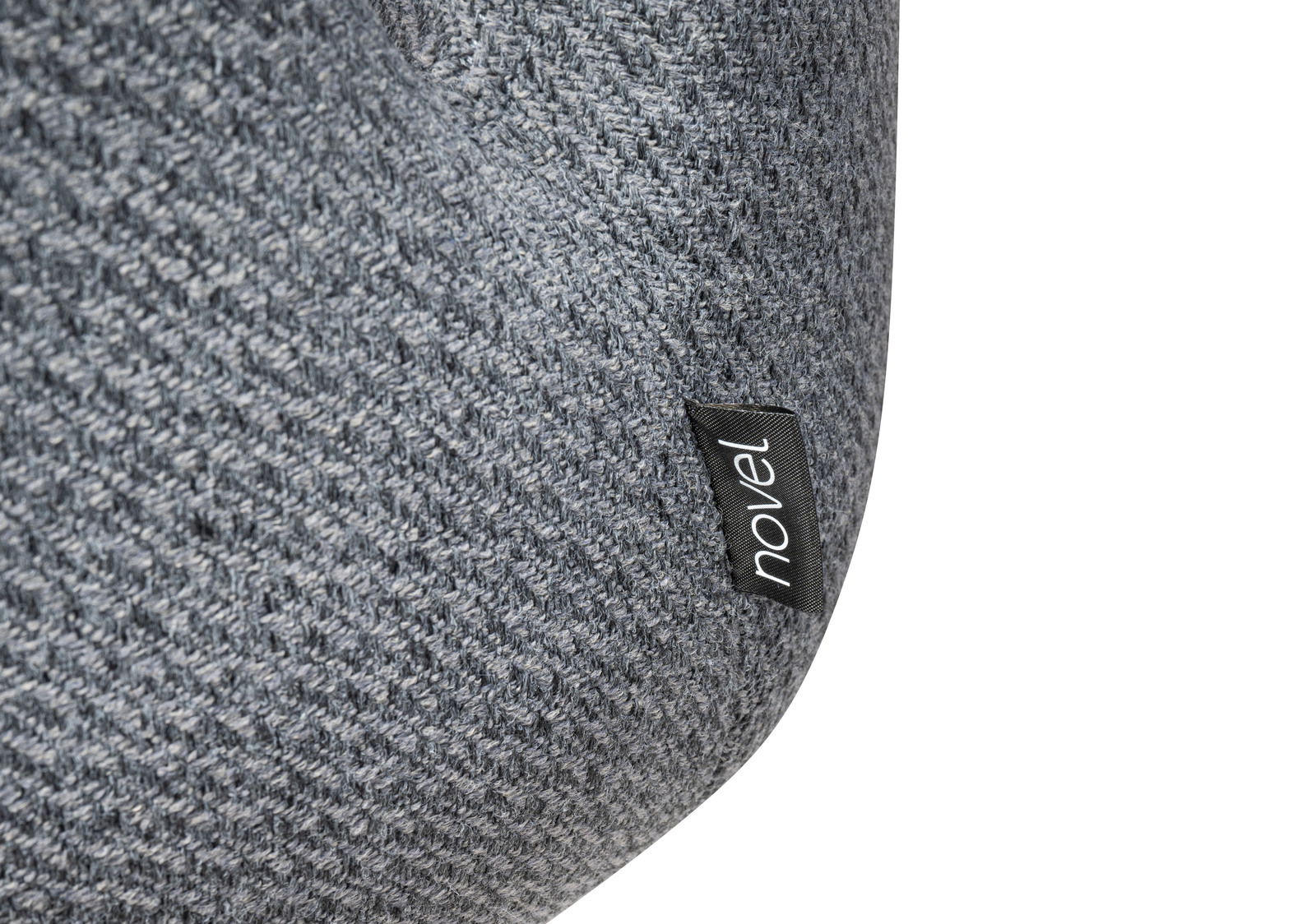 Nahaufnahme eines grauen Stoffes mit einer schwarzen Etikette mit der Aufschrift 'novel', perspektivisch von der Seite aufgenommen.