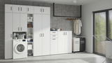 Moderne Waschküche mit weißen Mehrzweckschränken und Kommoden, Waschmaschine integriert, seitliche Perspektive.