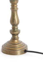 Nahaufnahme eines antik aussehenden Lampenfußes aus Metall mit Kabel, seitliche Perspektive.