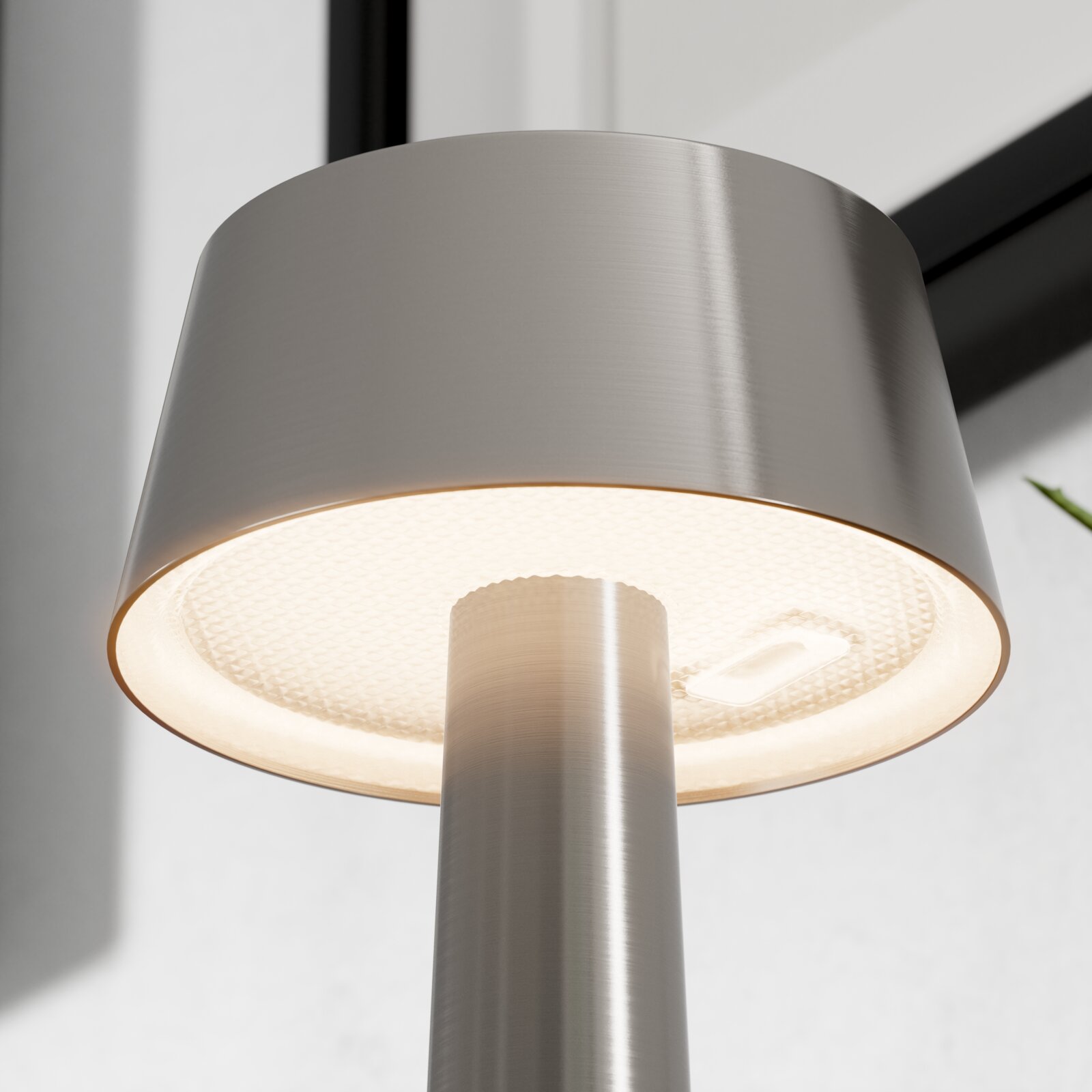 Nahaufnahme einer modernen LED-Stehleuchte aus gebürstetem Edelstahl mit zylindrischem Schirm und warmweiß leuchtendem Diffusor, fotografiert aus Untersicht (von unten nach oben)