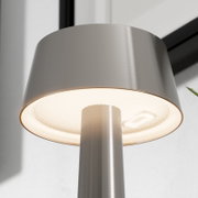 Nahaufnahme einer modernen LED-Stehleuchte aus gebürstetem Edelstahl mit zylindrischem Schirm und warmweiß leuchtendem Diffusor, fotografiert aus Untersicht (von unten nach oben)