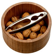 Runde Nussschale aus dunklem Bambus, gefüllt mit Walnüssen und einem Nussknacker, aus der Vogelperspektive.