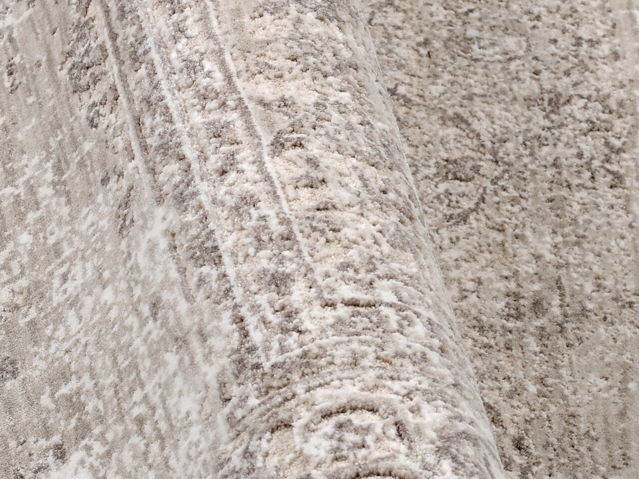 Nahaufnahme eines Designer-Teppichs mit detaillierter Textur und Muster in neutralen Tönen, seitliche Perspektive