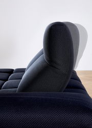 Seitenansicht einer verstellbaren Kopfstütze einer dunkelblauen Eckgarnitur mit strukturiertem Stoffbezug.