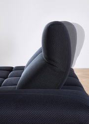Seitenansicht einer verstellbaren Kopfstütze einer dunkelblauen Eckgarnitur mit strukturiertem Stoffbezug.