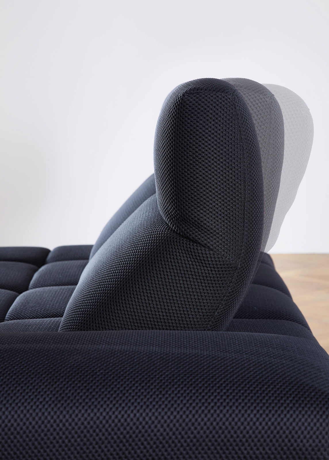 Seitenansicht einer verstellbaren Kopfstütze einer dunkelblauen Eckgarnitur mit strukturiertem Stoffbezug.