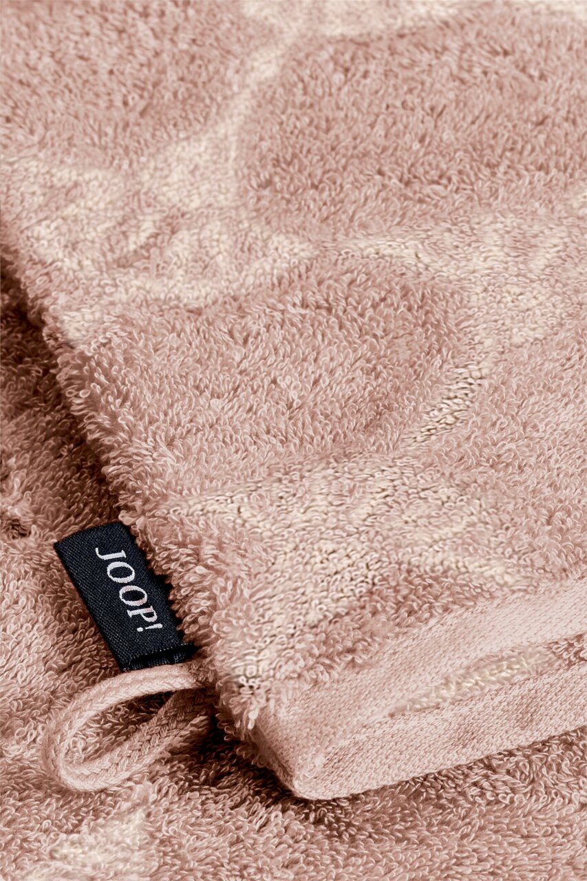 Nahaufnahme eines beigen Waschhandschuhs mit weicher Textur und einem schwarzen Etikett mit der Aufschrift 'JOOP!'