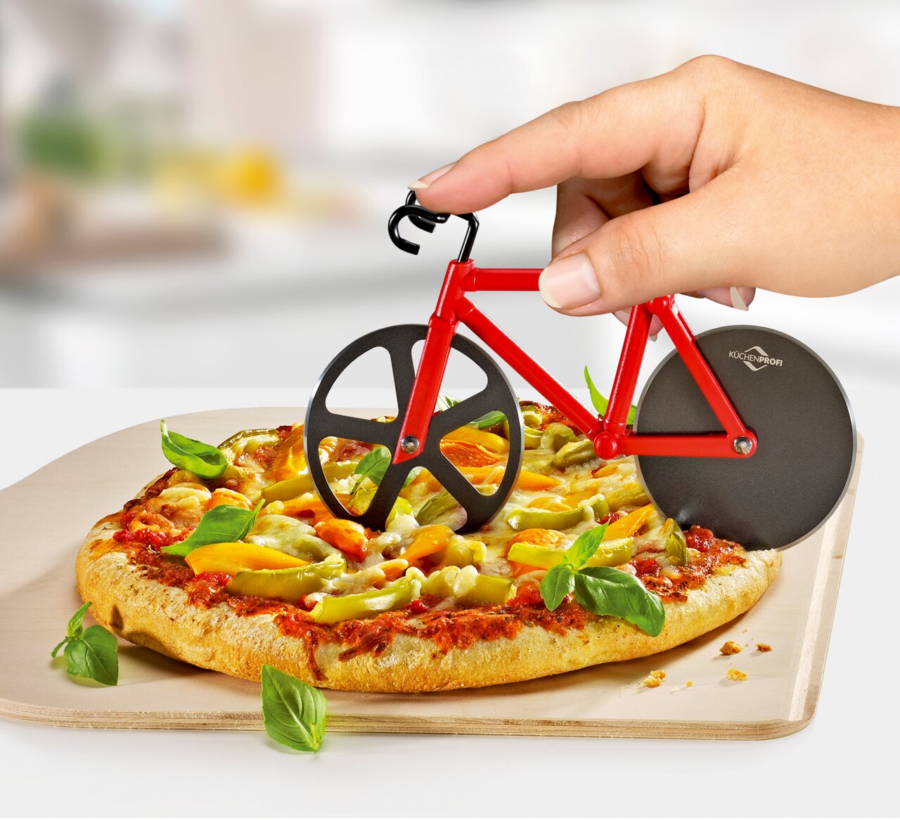 Pizzaschneider in Form eines Fahrrads, der von einer Hand gehalten wird und eine Pizza schneidet, seitliche Perspektive.