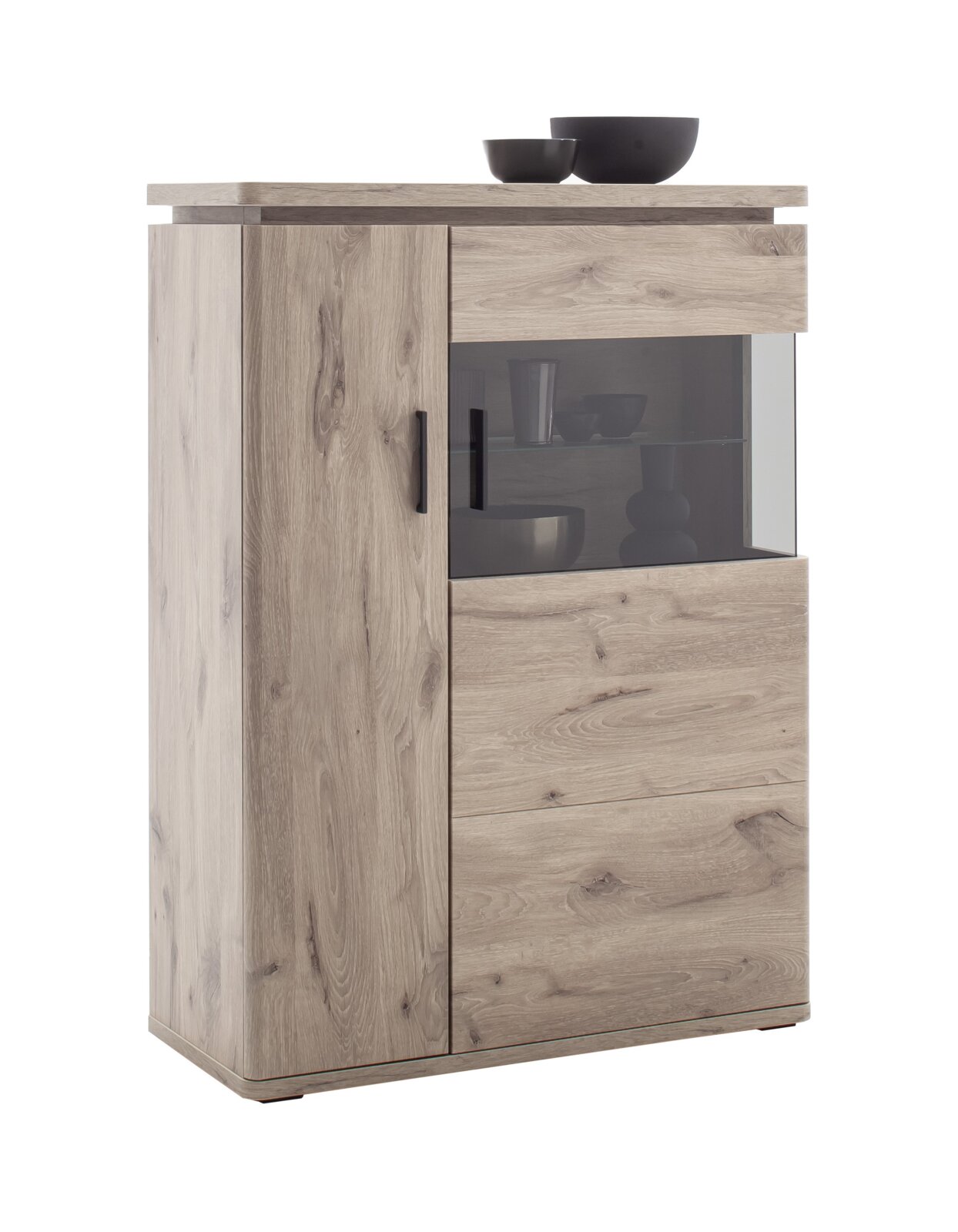Hoge houten ladekast in lichte eikenlook met een deur aan de linkerkant, een glazen vitrine aan de rechterkant en zwarte handgrepen; vooraanzicht licht van links op een witte achtergrond