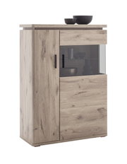 Hoge houten ladekast in lichte eikenlook met een deur aan de linkerkant, een glazen vitrine aan de rechterkant en zwarte handgrepen; vooraanzicht licht van links op een witte achtergrond