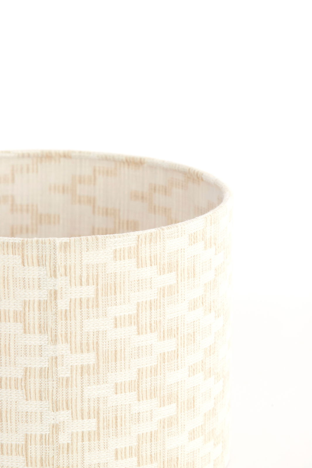 Nahaufnahme eines cremefarbenen Lampenschirms mit gewebtem Muster, seitliche Perspektive