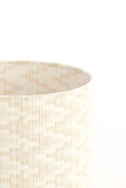 Nahaufnahme eines cremefarbenen Lampenschirms mit gewebtem Muster, seitliche Perspektive