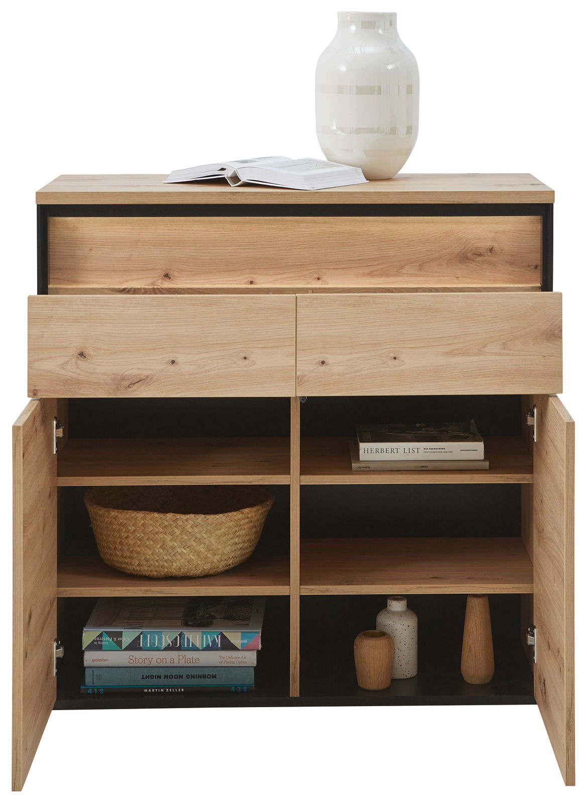 Kommode aus Holz mit zwei offenen Schubladen und zwei offenen Türen, die verschiedene Gegenstände wie Bücher, Körbe und Dekorationen zeigen. Perspektive von vorne.