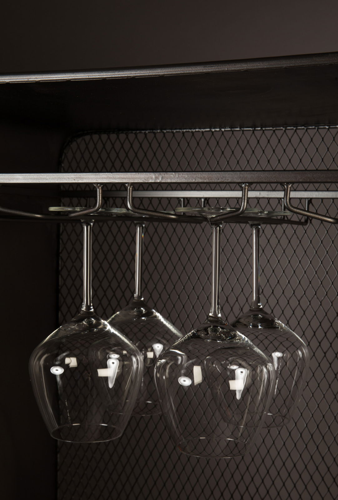 Nahaufnahme eines Weinregals mit hängenden Weingläsern, seitliche Perspektive.