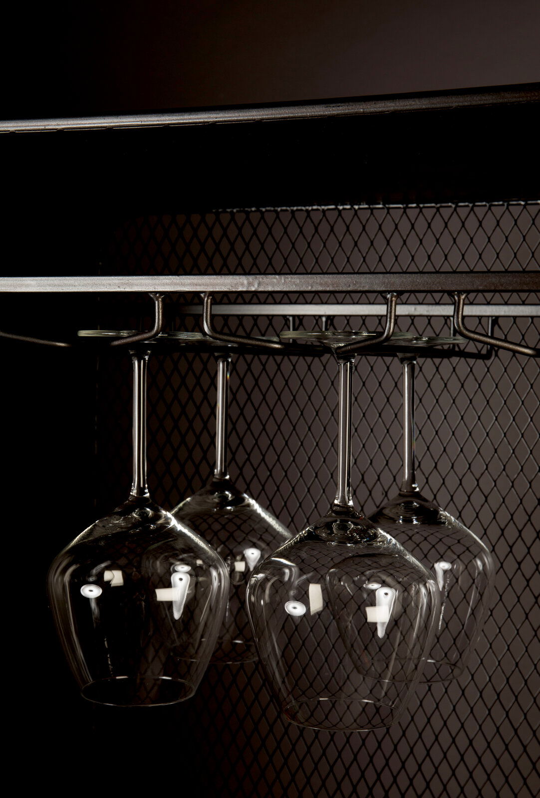 Nahaufnahme eines Weinregals mit hängenden Weingläsern, seitliche Perspektive.