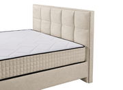 Beige Boxbett mit gestepptem Kopfteil und Matratze, seitliche Perspektive