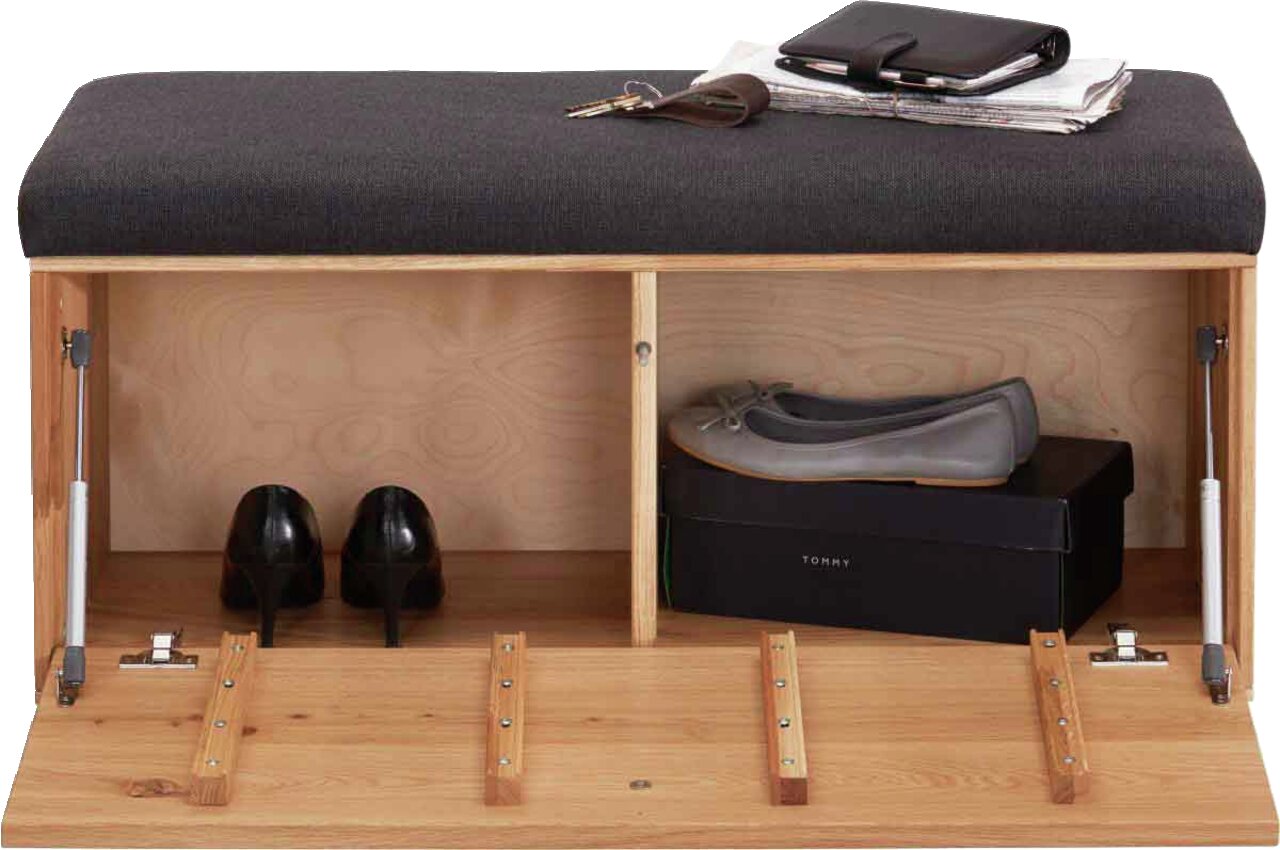 Garderobenbank mit gepolsterter Sitzfläche in dunklem Stoff, darunter Stauraum mit Schuhen und einer Schuhschachtel, aus hellem Holz, Perspektive von vorne.