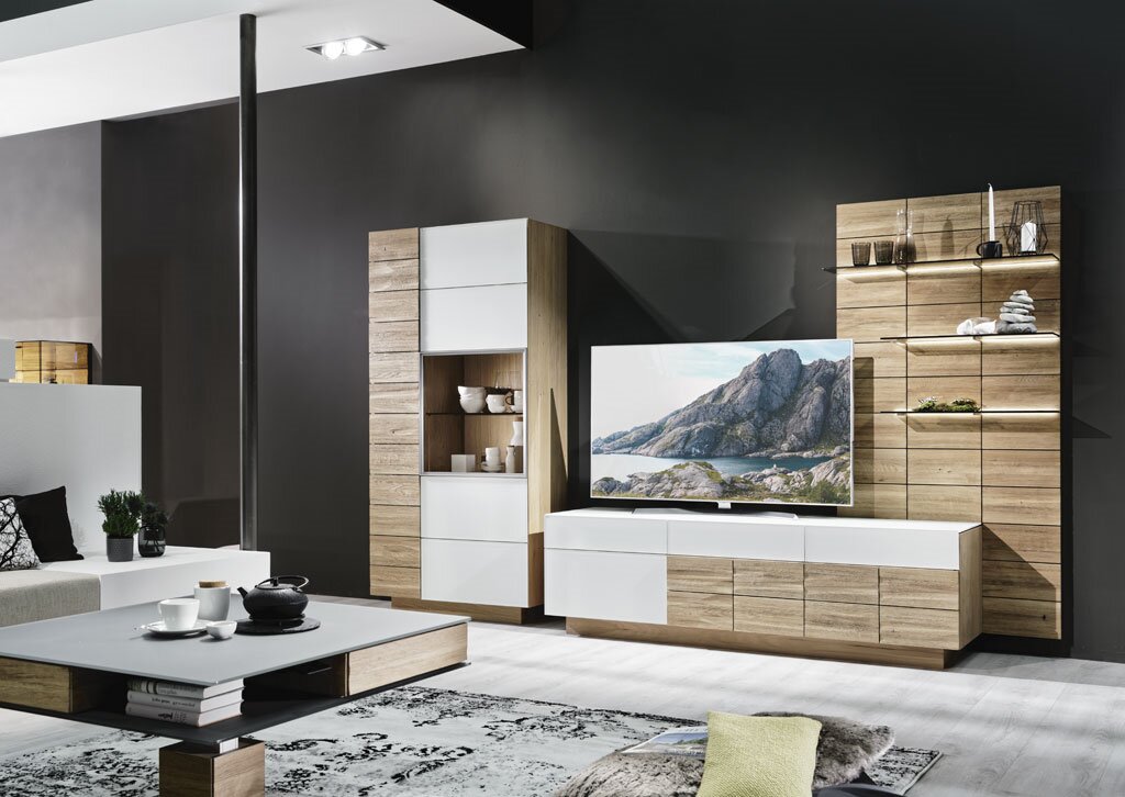 Modernes Wohnzimmerset aus Holzoptik und weißen Fronten mit TV-Lowboard, Vitrine und Regalwand, frontal in einem stilvollen Wohnzimmer inszeniert.