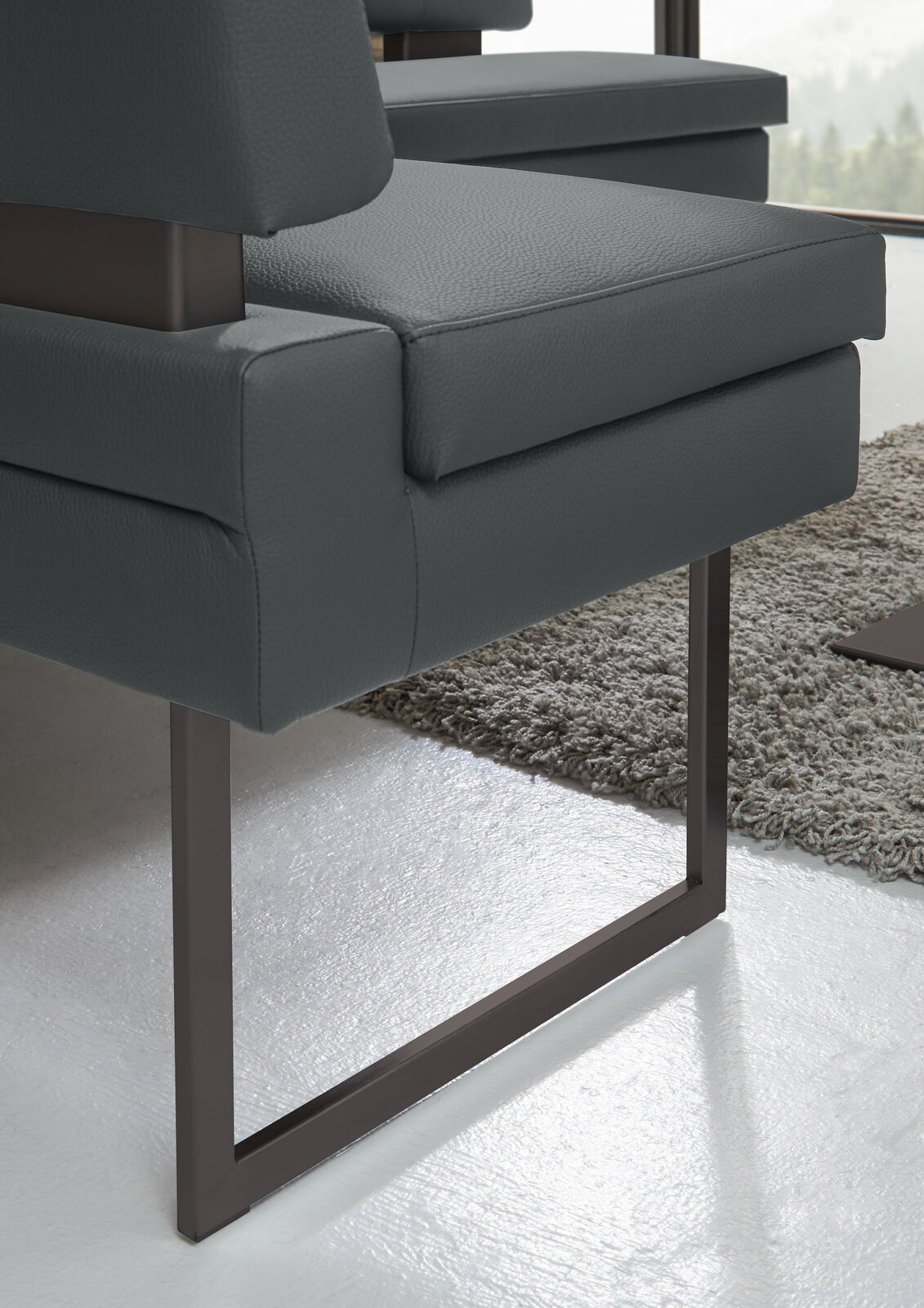 Nahaufnahme einer modernen Eckbank mit dunkelgrauem Polster und Metallgestell, seitliche Perspektive.