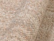 Nahaufnahme eines handgewebten Teppichs in natürlichen Beige- und Brauntönen, mit einer strukturierten, gewellten Oberfläche.