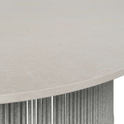 Nahaufnahme einer Tischplatte aus hellem Stein mit geflochtenem Seil als Tischbein, seitliche Perspektive.