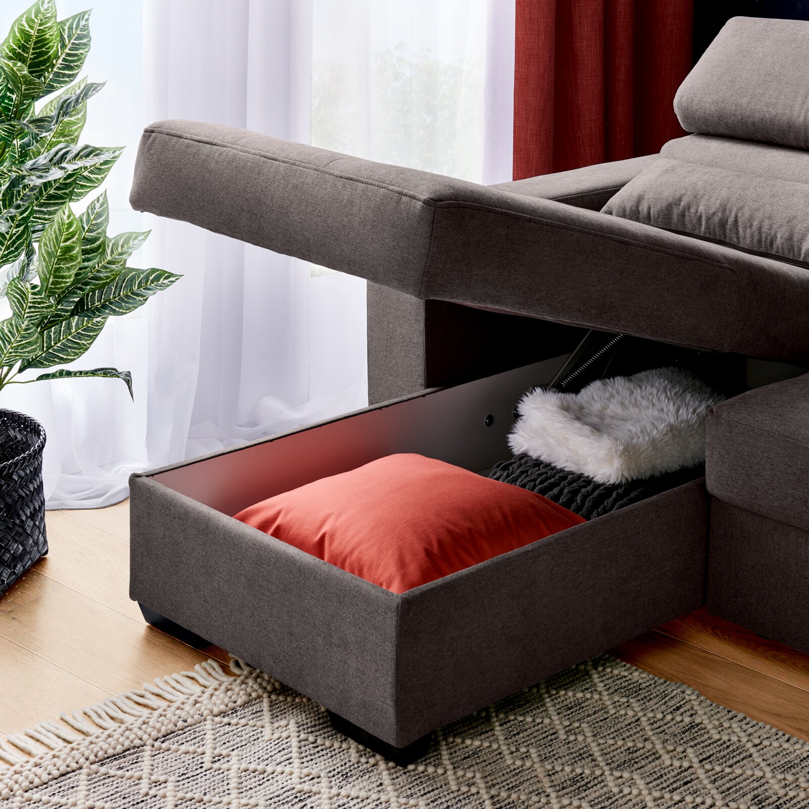 Graue Rundecke mit Stauraum, geöffnet, mit Kissen und Decke, seitliche Perspektive
