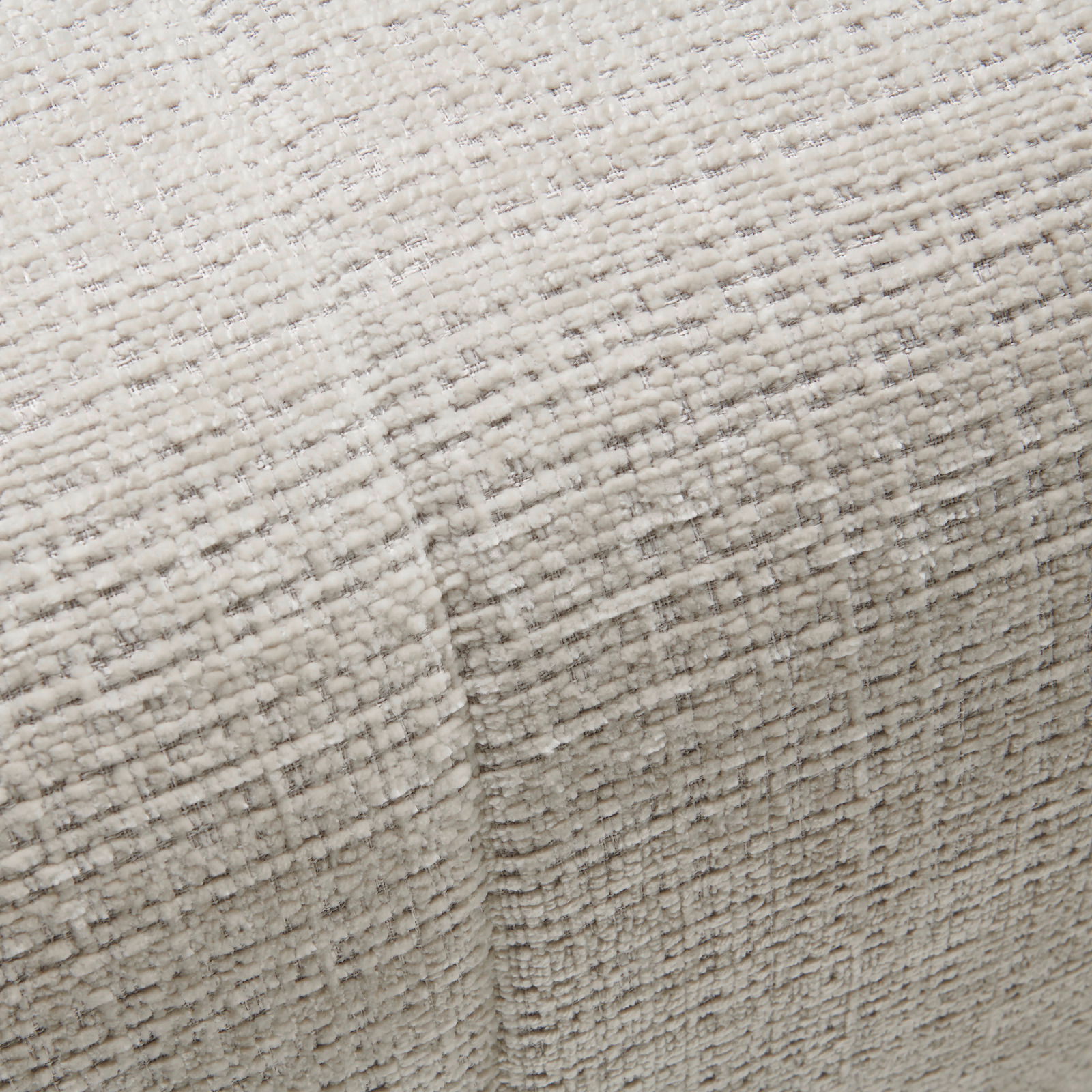 Nahaufnahme einer strukturierten, hellen Stoffoberfläche mit gewebtem Muster, perspektivisch von oben betrachtet.