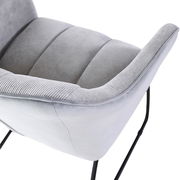 Nahaufnahme eines grauen Armlehnstuhls mit weichem Stoffbezug und schwarzen Metallbeinen, seitliche Perspektive