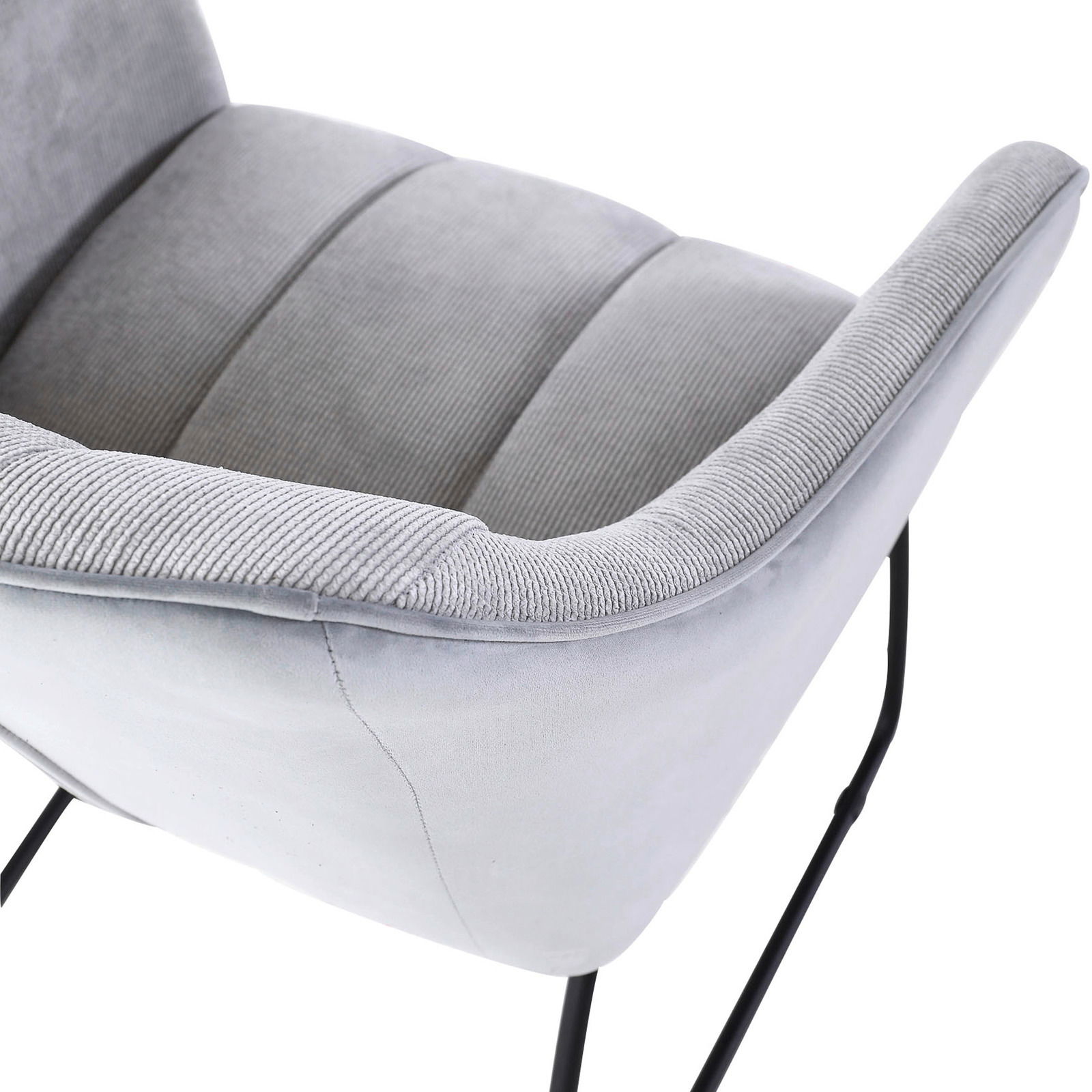 Nahaufnahme eines grauen Armlehnstuhls mit weichem Stoffbezug und schwarzen Metallbeinen, seitliche Perspektive