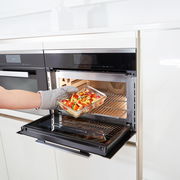 Rechteckige Glasform mit 1,30 L Fassungsvermögen, gefüllt mit Gemüse, wird aus einem modernen Backofen entnommen. Seitliche Perspektive.