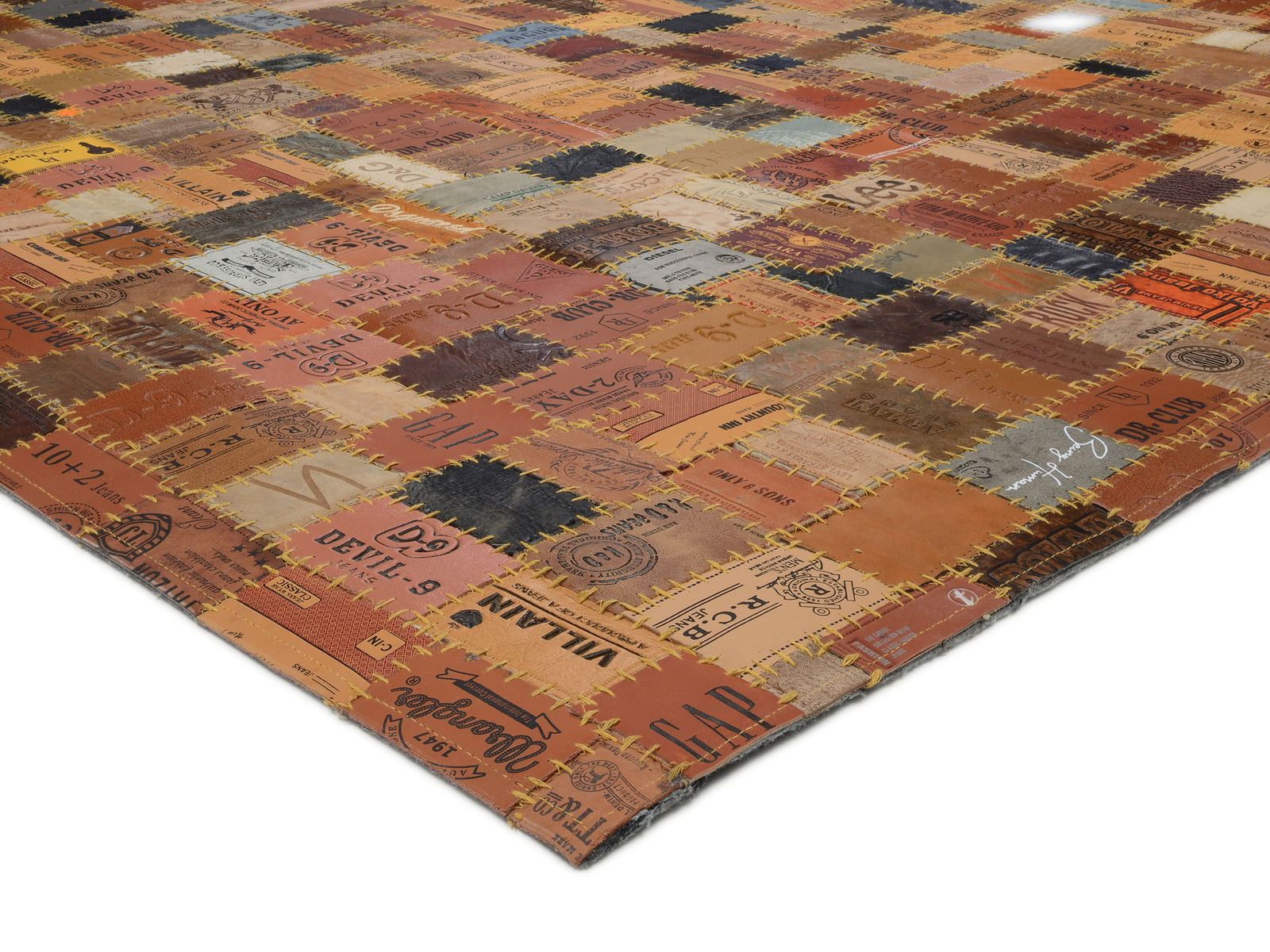 Lederteppich aus verschiedenen rechteckigen Lederstücken mit aufgedruckten Logos und Schriftzügen, perspektivisch von der Seite fotografiert.