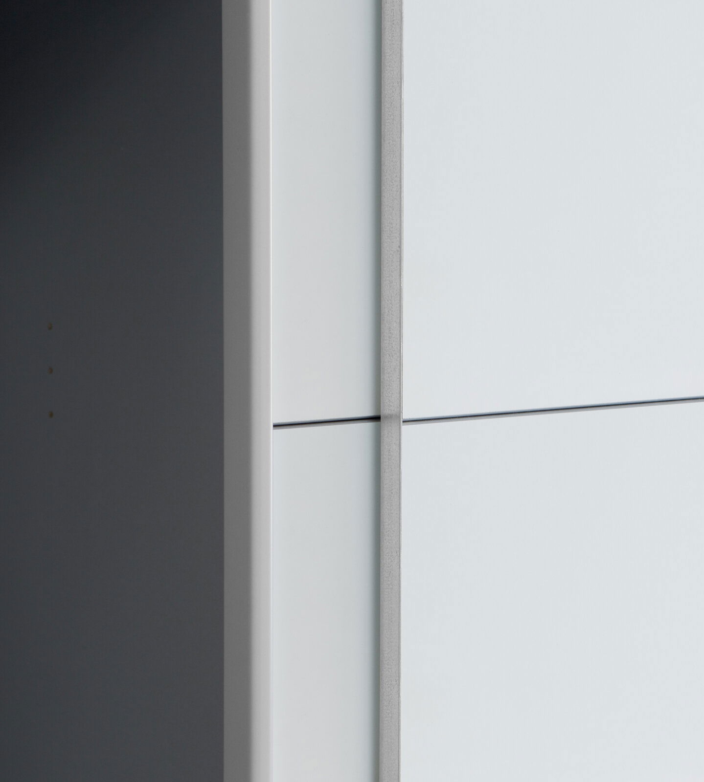 Nahaufnahme eines Dreh- und Schwebetürenschranks aus seitlicher Perspektive mit glatter, heller Oberfläche.