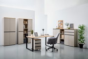 Moderne Büromöbel in einem hellen Raum, bestehend aus einem Schreibtisch mit Rollcontainer, mehreren Aktenschränken und einem Kombischrank. Perspektive von vorne.