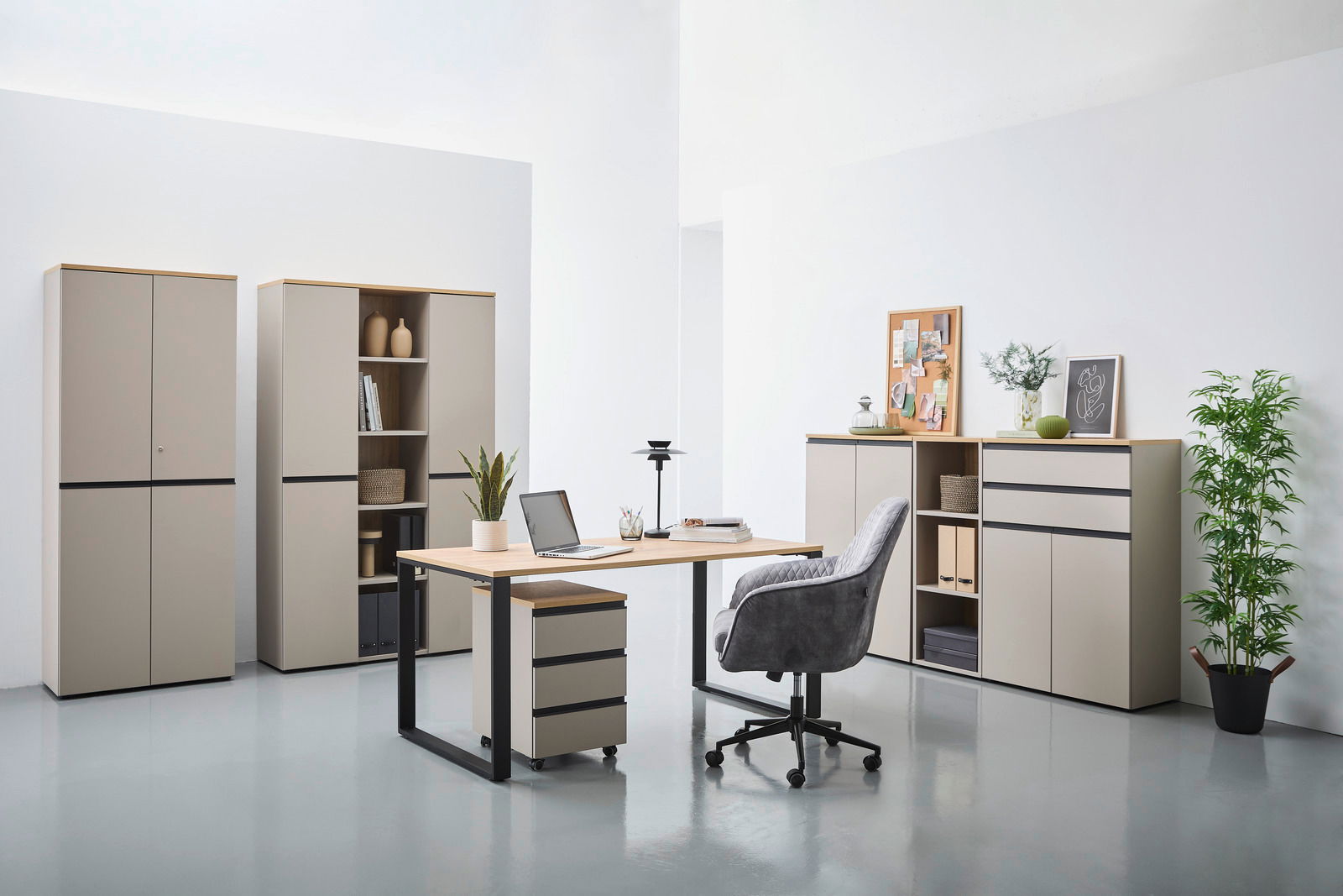 Moderne Büromöbel in einem hellen Raum, bestehend aus einem Schreibtisch mit Rollcontainer, mehreren Aktenschränken und einem Kombischrank. Perspektive von vorne.