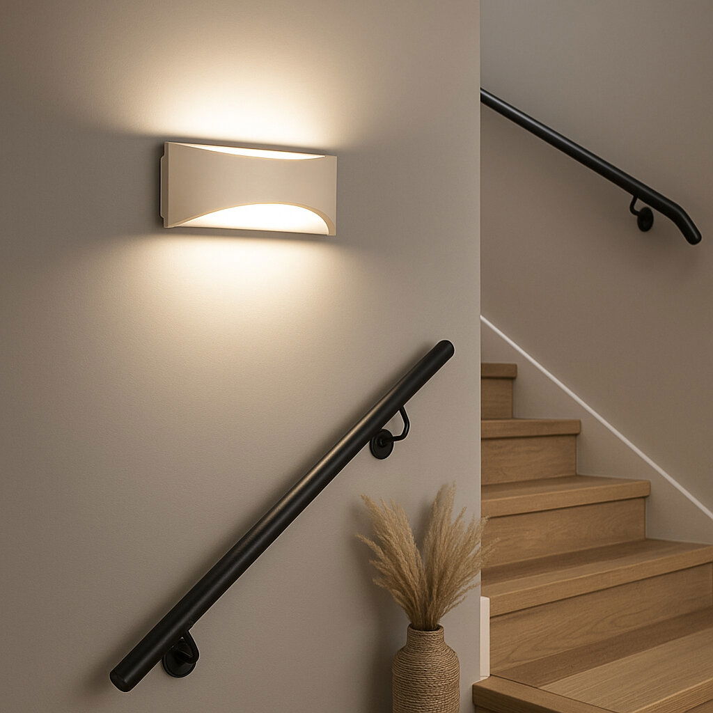 Moderne weiße Wandleuchte im Treppenhaus, die warmes Licht nach oben und unten abstrahlt; Perspektive: seitliche Frontansicht auf die Leuchte an der Wand neben der Treppe.