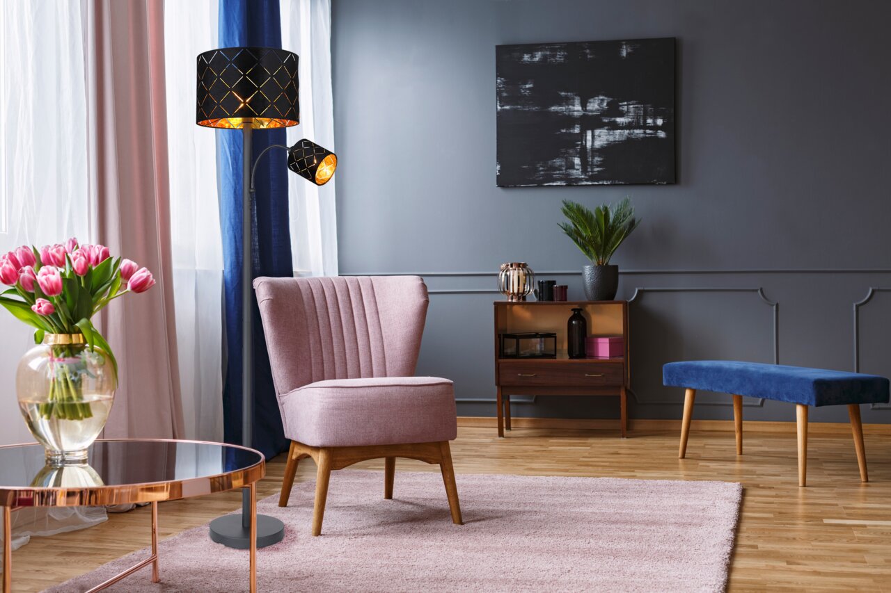 Moderne Stehleuchte mit schwarzem, gemustertem Lampenschirm in einem stilvoll eingerichteten Wohnzimmer, seitliche Perspektive.