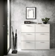 Moderner weißer Schuhkipper mit sechs Fächern, frontal fotografiert, in einem stilvollen Eingangsbereich mit grauer Wand, dekoriert mit einer Pflanze, einer Uhr und einem Kunstwerk.