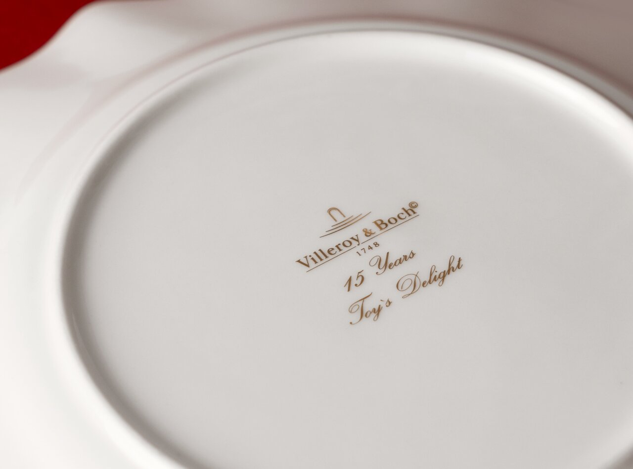 Achterkant van een jubileumbord van Villeroy & Boch met het gouden opschrift '15 Years Toy's Delight'.