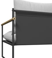 Detailansicht eines Gartenlounge-Sessels mit schwarzem Metallrahmen, hellgrauen Kissen und Holzarmlehne von der Seite.