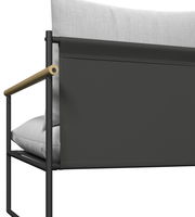 Detailansicht eines Gartenlounge-Sessels mit schwarzem Metallrahmen, hellgrauen Kissen und Holzarmlehne von der Seite.