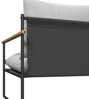 Detailansicht eines Gartenlounge-Sessels mit schwarzem Metallrahmen, hellgrauen Kissen und Holzarmlehne von der Seite.