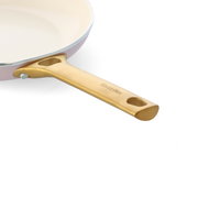 Nahaufnahme eines Topfes mit goldenem Griff und heller Innenbeschichtung, seitliche Perspektive