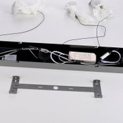 Innenansicht einer schwarzen LED-Leuchte mit sichtbar verlegter Verkabelung, Netzteil und Lüfter sowie separater Metall-Montagehalterung auf weißem Hintergrund, fotografiert aus leicht erhöhter Draufsicht.