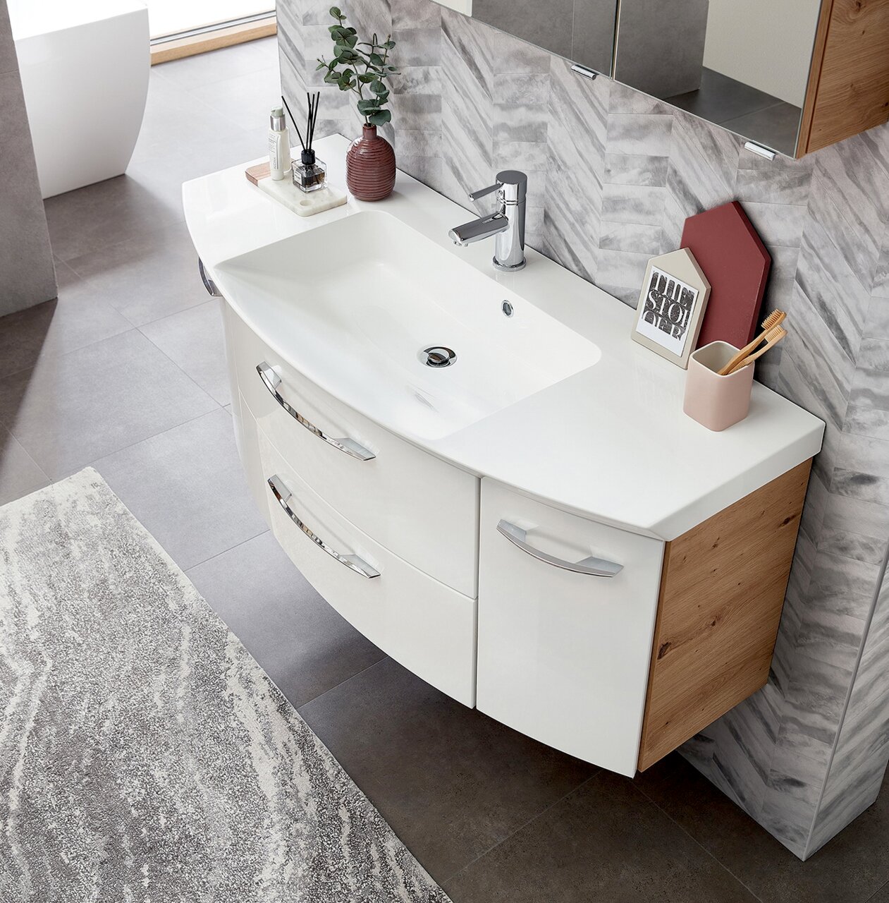 Moderne badkamercombinatie met een witte wastafel en houten kasten, gefotografeerd van bovenaf.