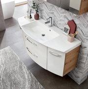 Moderne badkamercombinatie met een witte wastafel en houten kasten, gefotografeerd van bovenaf.