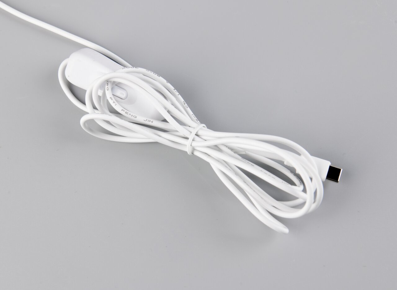 Weißes USB-Ladekabel mit integriertem Ein-/Aus-Schalter, aufgewickelt auf grauem Hintergrund, fotografiert aus schräger Draufsicht