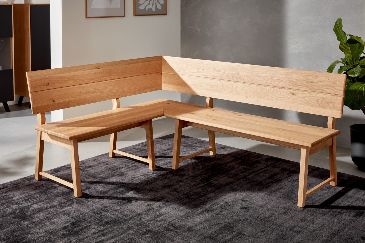 Eckbank aus Holz in L-Form, seitliche Perspektive, auf einem dunklen Teppich in modernem Raum