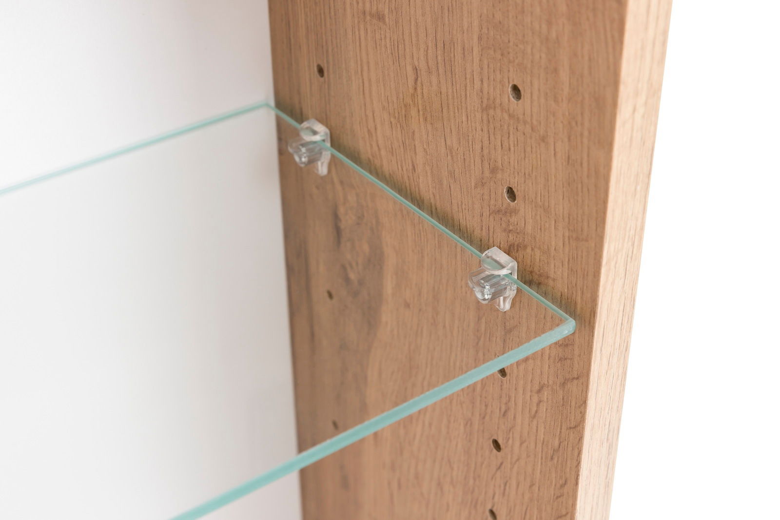 Nahaufnahme eines Spiegelschranks mit einem Glasregal, das an einer Holzwand befestigt ist. Perspektive von der Seite.