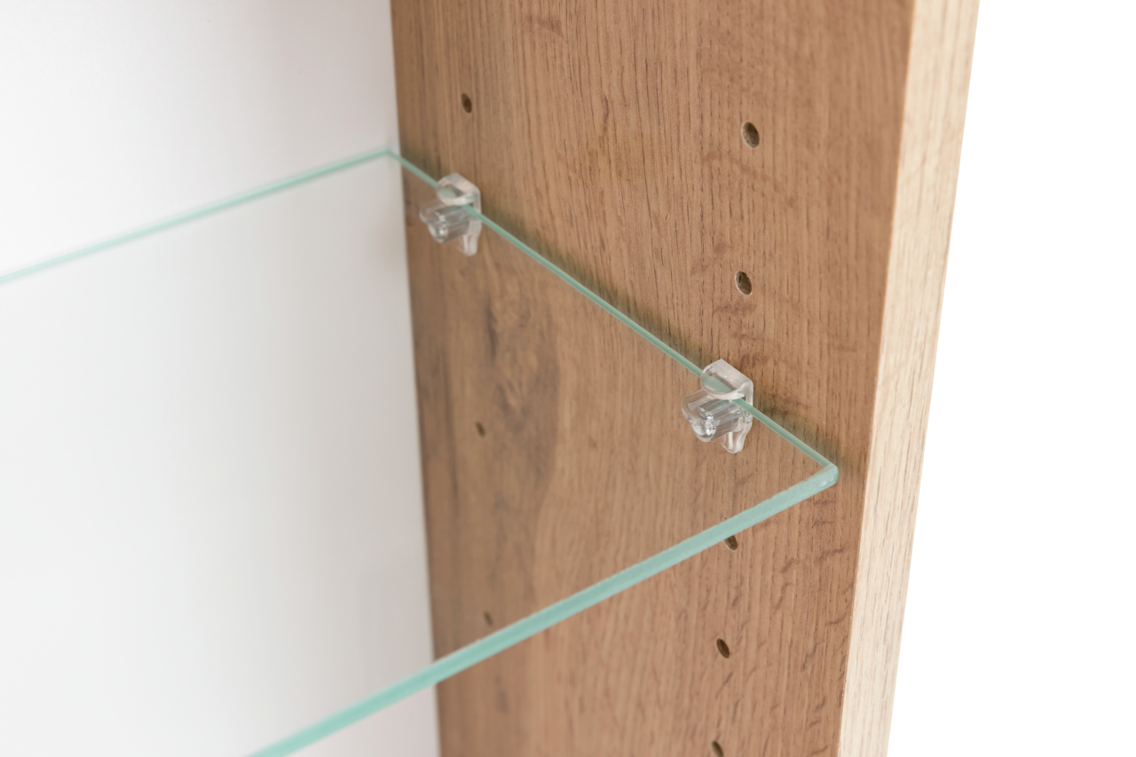 Nahaufnahme eines Spiegelschranks mit einem Glasregal, das an einer Holzwand befestigt ist. Perspektive von der Seite.