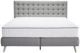 Frontale Ansicht eines grauen Boxspringbetts mit gestepptem Kopfteil und weißer Matratze.